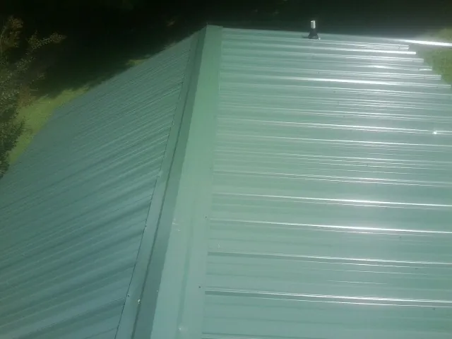 New green metal panels meeting at the ridge of a roof — Flat Roof Repair work by our crew in Flandreau