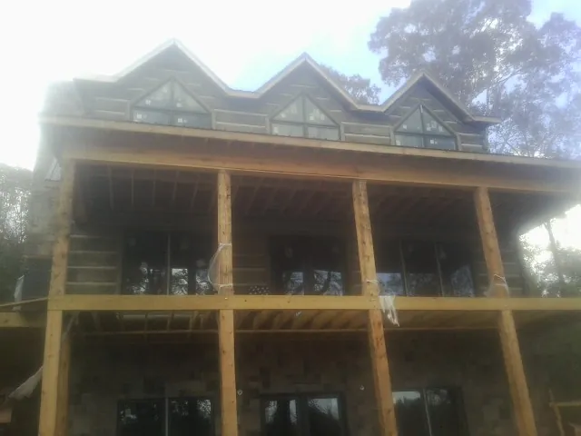 Dormers and porch framing on a large log home under construction — Roof Coating work by our crew in Flandreau