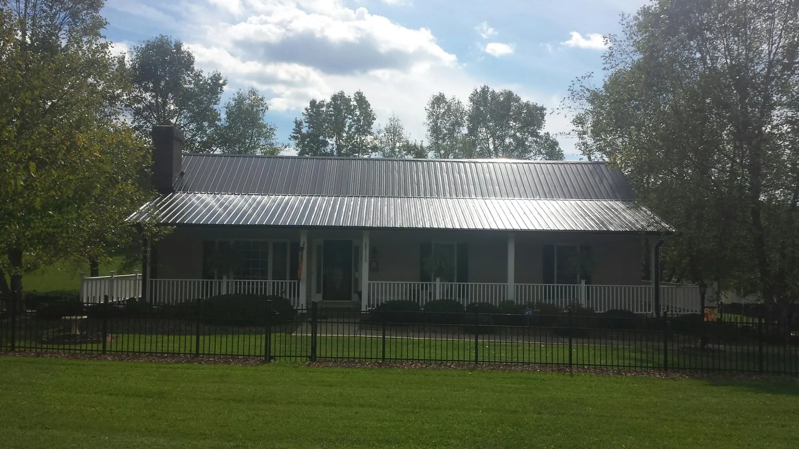 Gray metal roof on a brick ranch with a full width front porch — Gutter Guard Installation work by our crew in Flandreau