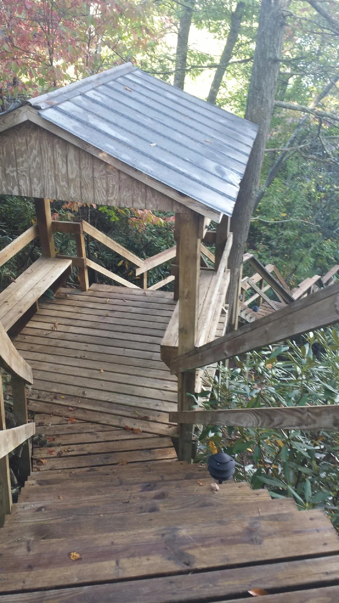 Metal roofed shelter over wooden steps on a wooded walkway — Skylight Repair & Installation work by our crew in Flandreau