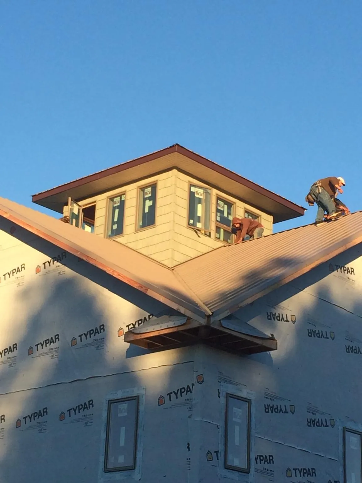 Roofers working around a rooftop cupola on a new metal roof at sunset — Roof Waterproofing in Flandreau by Roofing Brothers